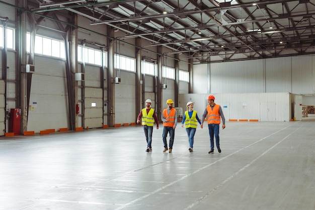 Group of smiling professional managers engineers workers walking in warehouse