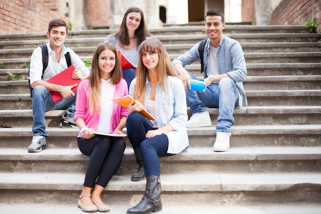 Gruppo di studenti sorridenti che si siedono su una scala