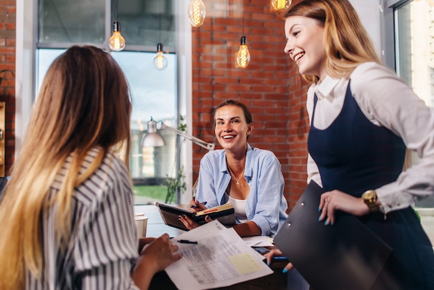 group of smiling women discussing in office