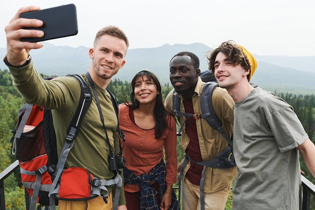 Группа улыбающихся молодых многонациональных друзей-пешеходов, позирующих для селфи на фоне лесного пейзажа во время