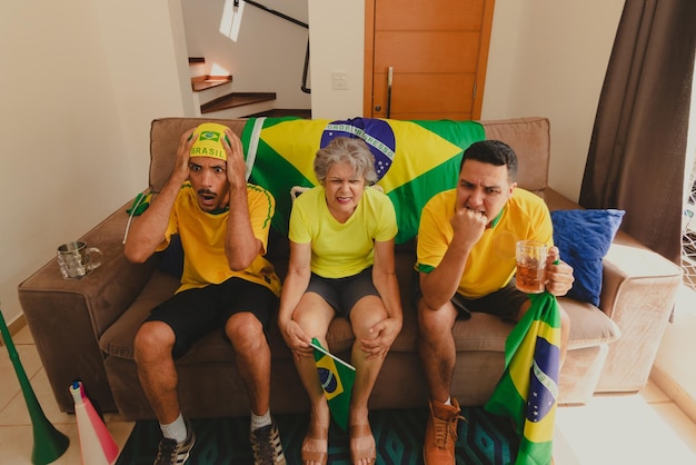 Group of soccer fans celebrating the cup in the living room\
watching football game