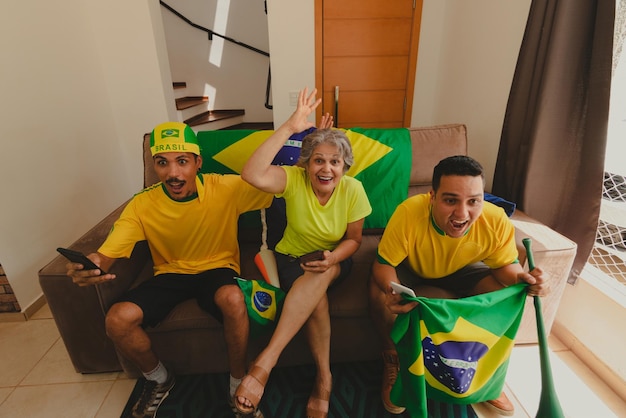 Photo group of soccer fans celebrating the cup in the living room watching football game