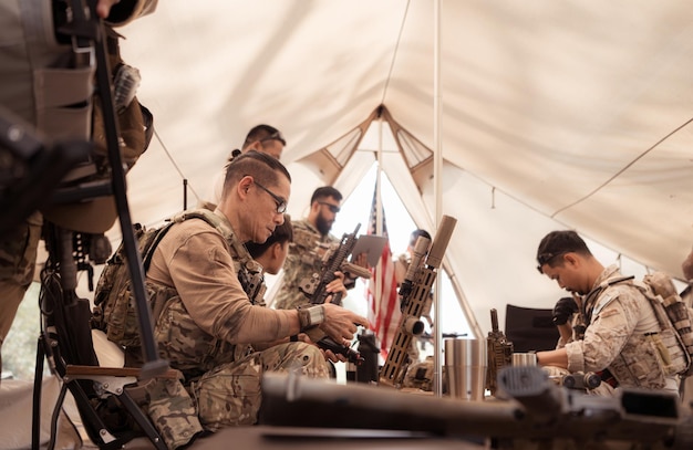 Foto un gruppo di soldati in uniforme di camuffamento tiene le armi in una tenda da campo pianificare e preparare