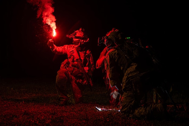 Group of soldiers in camouflage uniforms hold weapons with patrol missions at night