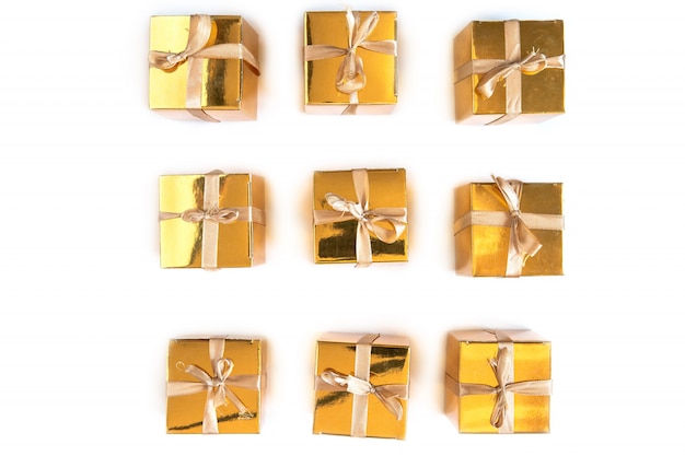 Group of sparkling gold present or gift boxes in a row with bow isolated