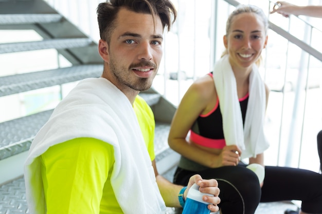 Group of sporty people relaxing and talking after class in gym.