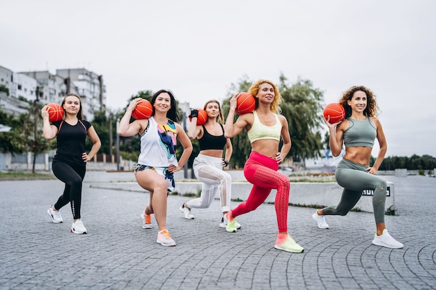 group of sporty women performing exercises with orange balls