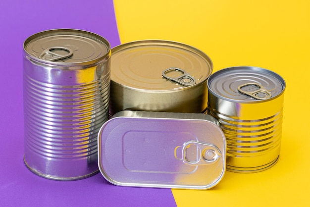 分割された黄色と紫の背景に空白のエッジを持つ積み重ねられたブリキ缶のグループ