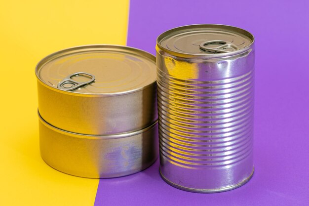 分割された黄色と紫の背景に空白のエッジを持つ積み重ねられたブリキ缶のグループ