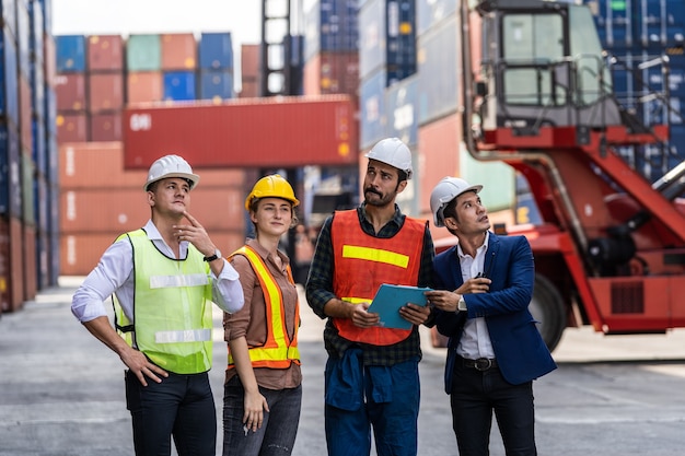 Gruppo di lavoratori del personale in piedi e controllando la scatola dei contenitori dalla nave da carico per l'esportazione e l'importazione