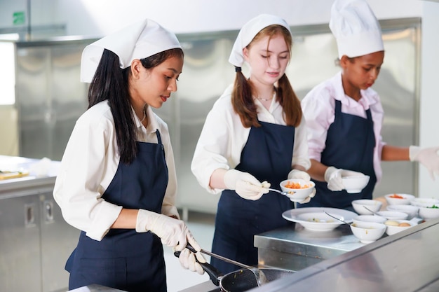 요리 교실 요리 교실을 배우는 여학생 그룹 행복한 젊은 여성 다민족 학생들이 요리 학교에서 요리 수업에 집중하고 있습니다