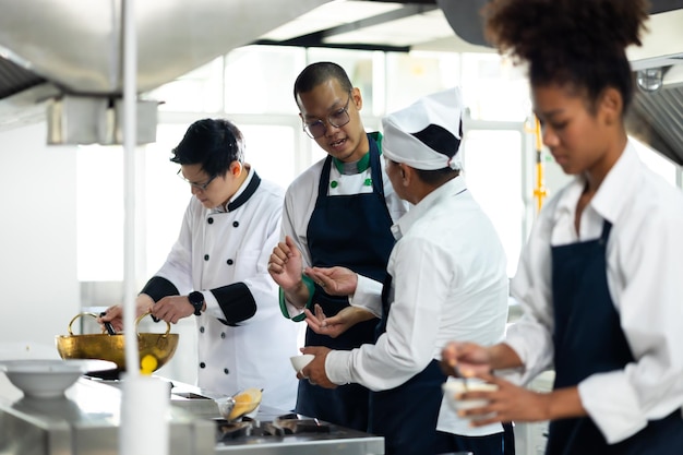 料理教室 - 料理の教室 熟成した男性と若い女性のグループ 複数の民族の学生が料理学校で料理のレッスンに焦点を当てています