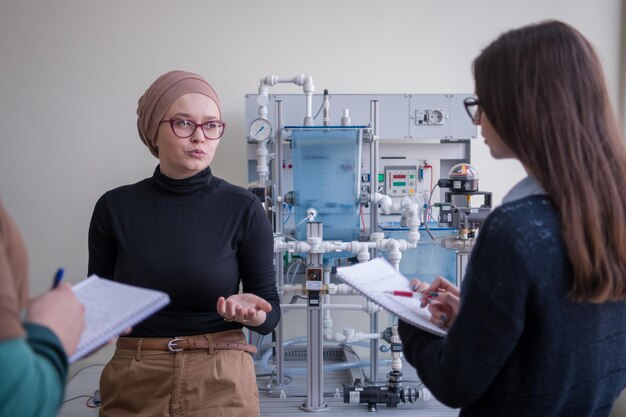 Group of students doing technical vocational practice with young female muslim teacher in the electronic classroom, Education and technology concept