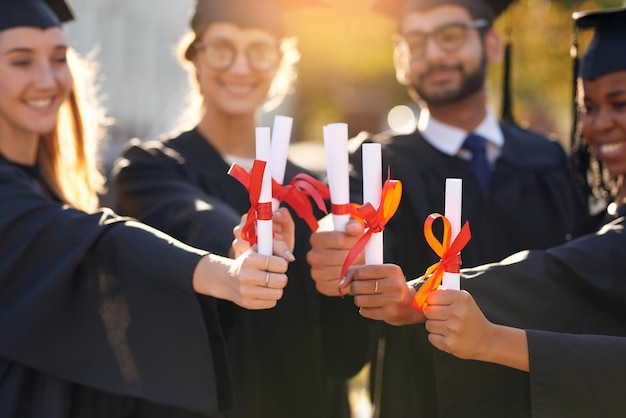 Foto studenti di gruppo e diploma di laurea con le mani degli amici del college o dell'università uomini e donne all'aperto per celebrare il successo dell'istruzione e il certificato a scuola per i laureati