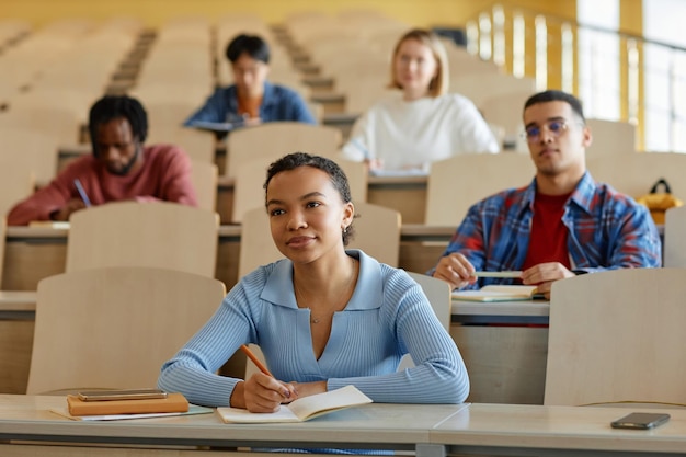 Foto gruppo di studenti che ascoltano il docente seduti alla scrivania con libri di testo durante la lezione all'università