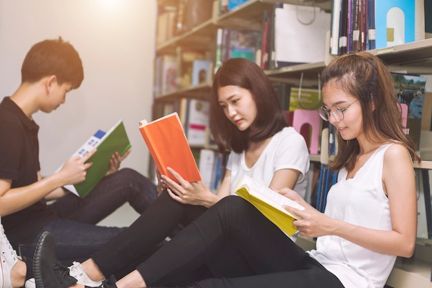 Группа студентов читает на пол в библиотеке. Концепция образования.