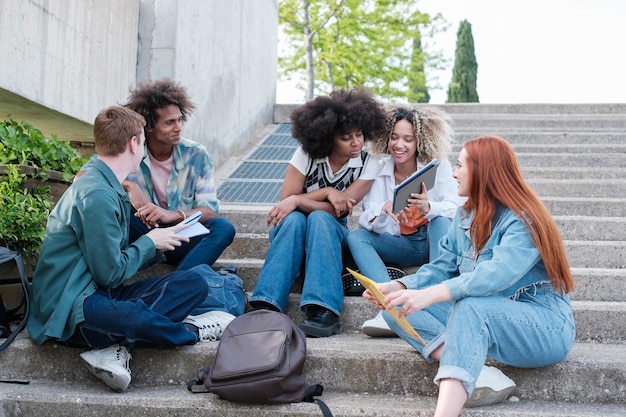 Group of students sharing notes sitting outdoors on the university campus Concept studies education university