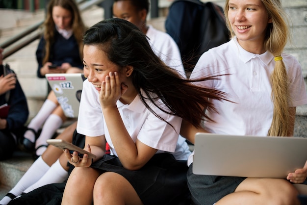 Photo group of students sitting on staircase using lptop