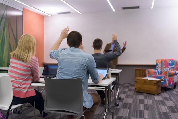 学生のグループは、現代の学校の教室で教授と一緒に勉強します