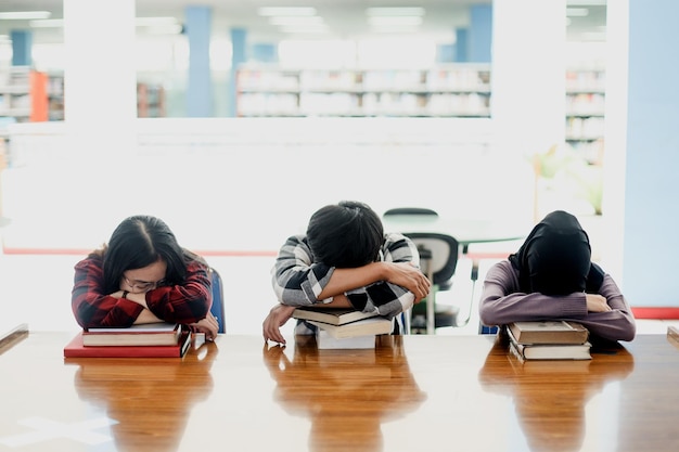 Group of students studying hard for exam and sleeping on books in the library