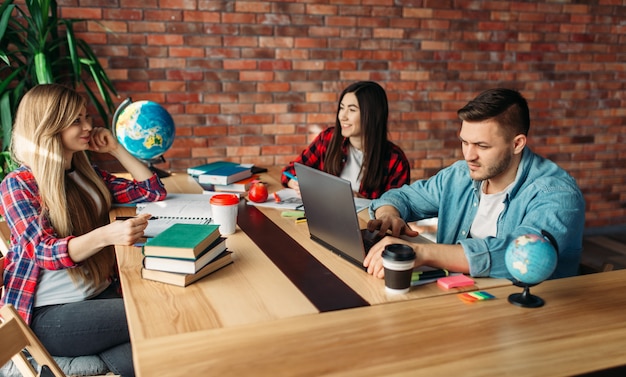 Group of students studying at the table together. People with laptop surfing information in internet