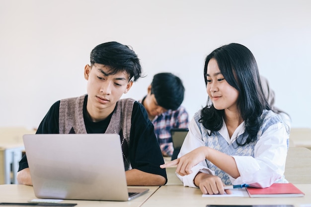 Group of students using laptop while studying in college classroom