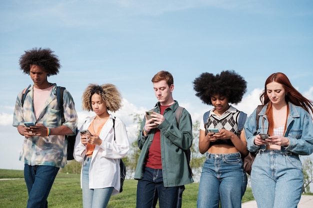 group of students walking through the university campus looking only at the mobile concept smartphone digital age entertainment
