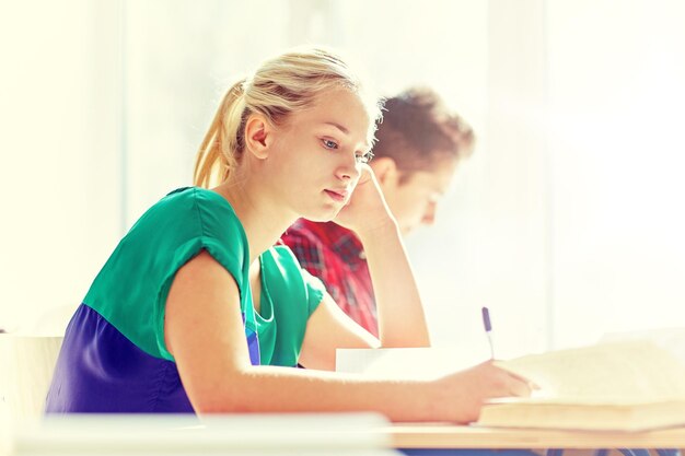 Gruppo di studenti con libri che scrivono test scolastici