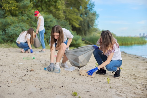 Group of students with teacher in nature doing cleaning of plastic garbage. Environmental protection, youth, volunteering, charity, and ecology concept