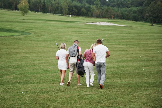 Gruppo di amici alla moda sul campo da golf imparano a giocare a un nuovo gioco. la squadra si riposerà dopo la partita