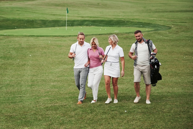 Gruppo di amici alla moda sul campo da golf imparano a giocare a un nuovo gioco. la squadra si riposerà dopo la partita