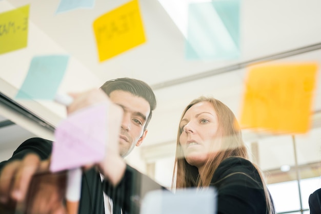 Group of successful business teamwork Brainstorm meeting with colorful sticky paper note on glass wall for new ideas Using agile methodology and do business Brainstorming in a tech startup office