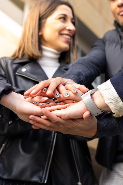Group of successful young people interlocking hands in the street Smiling group of successful young people putting hands together on top of each other