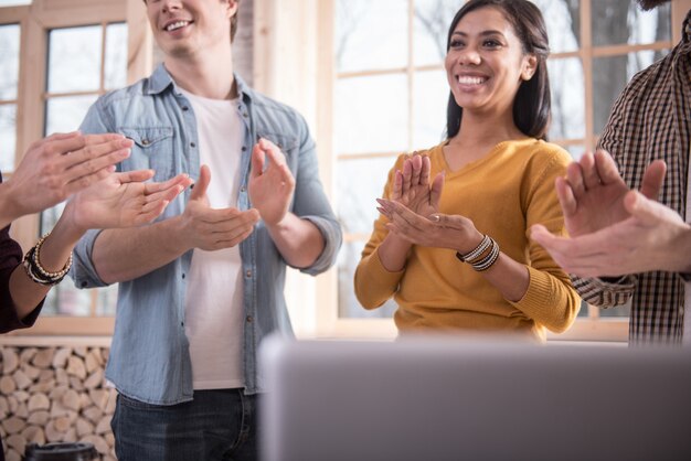 Group support. Happy delighted positive people standing together and applauding while being in a great mood