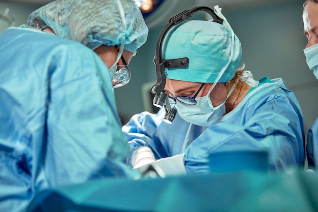 Group of surgeons looking at patient on operation table during their work