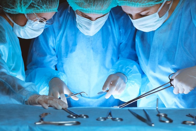 Group of surgeons wearing safety masks performing operation.\
close-up of surgery tools. medicine concept