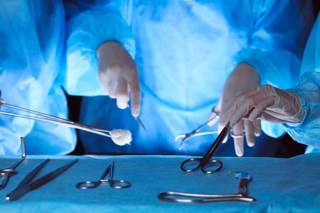 Group of surgeons wearing safety masks performing operation. Close-up of surgery tools. Medicine concept