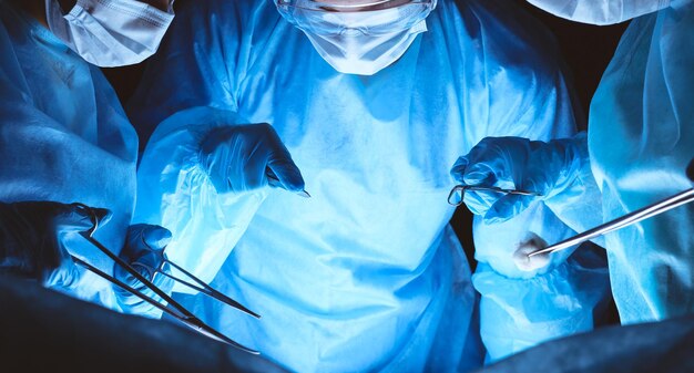 Group of surgeons wearing safety masks performing operation. Medicine concept.