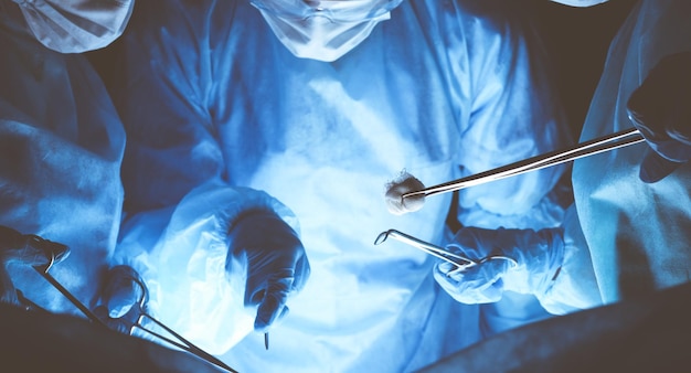 Photo group of surgeons wearing safety masks performing operation. medicine concept.