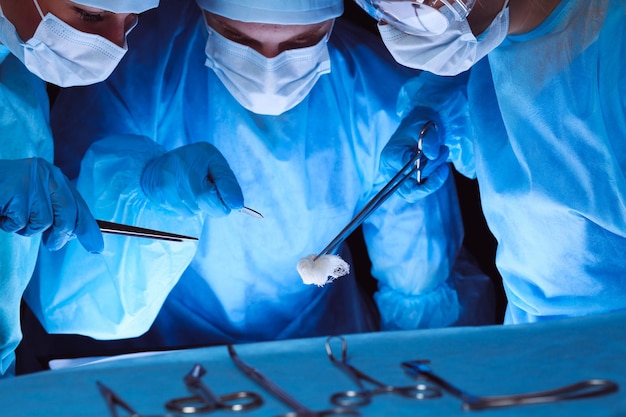 수술을 수행하는 안전 마스크를 착용한 외과의사 그룹. 의학 개념입니다.