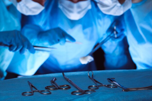 Group of surgeons wearing safety masks performing operation. Medicine concept.