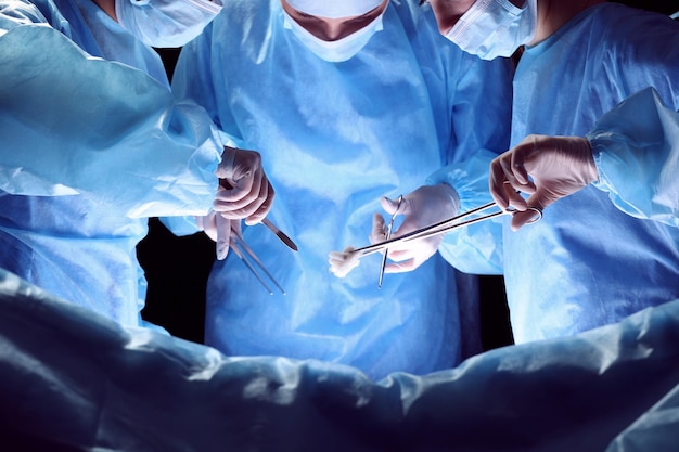 파란색 톤의 수술실에서 일하는 외과의사 그룹. 수술을 수행하는 의료 팀