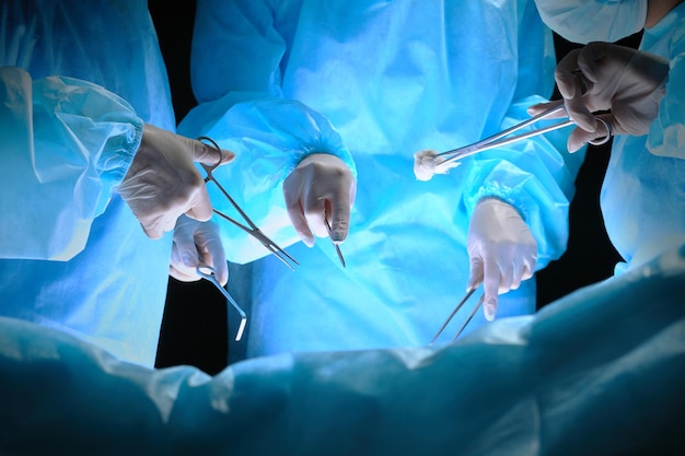 Group of surgeons at work in operating theater toned in blue