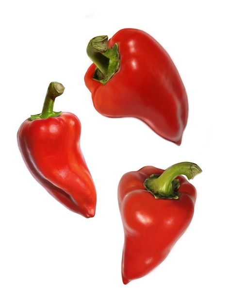 A group of sweet red bell peppers in flight on a white background