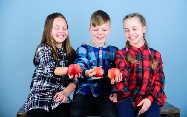 Group teenagers cheerful kids hold apples Boy and girls friends eat apple Teens with healthy snack Healthy dieting and vitamin nutrition Eat fruit and be healthy Promoting healthy nutrition