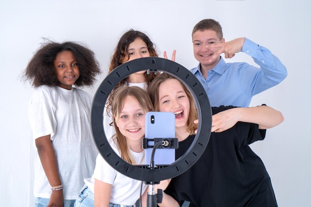 A group of teenagers shoot a video on phone on a tripod Selfie