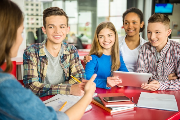 Group of teenagers sitting at the table in cafe.