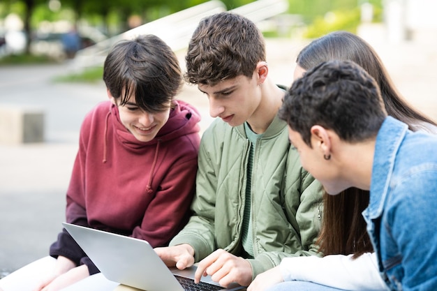 Group of teenagers working on laptop outdoors