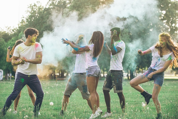 Group of teens playing with colors at the holi festival, in a park