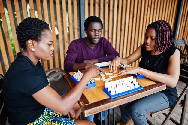 Group of three african american friends play table games.